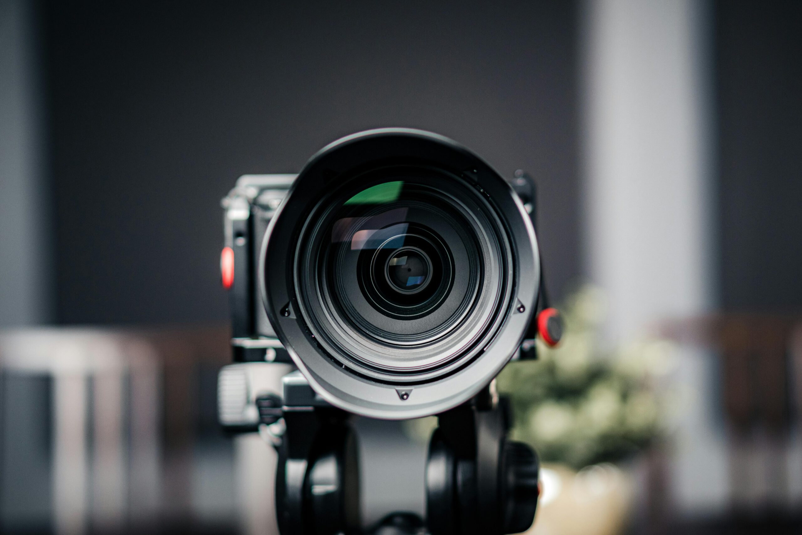 Close-up of a professional camera lens with a blurred background, focusing on the lens details.